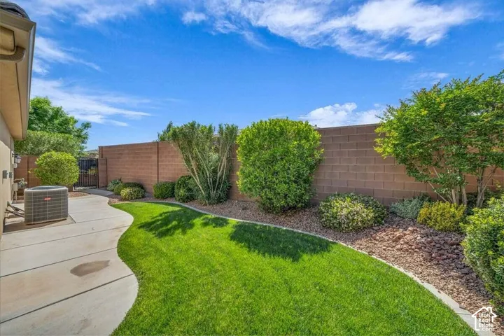 Expansive backyard featuring a manicured lawn, curved concrete pathway, and a perimeter wall with mature landscaping