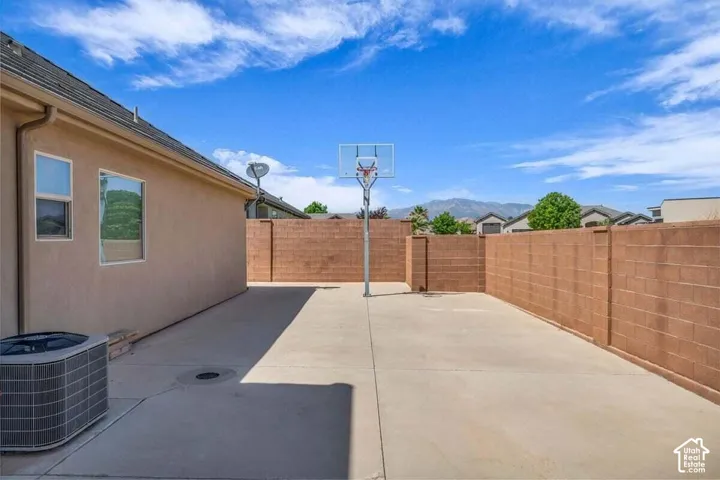 Paved concrete patio area with block wall fencing and a basketball hoop