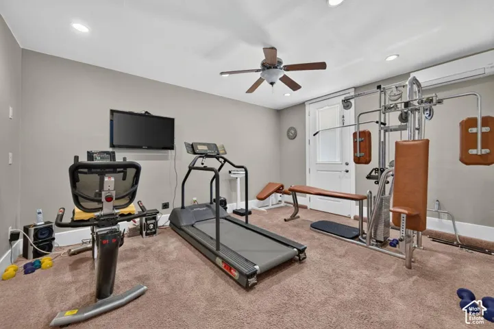 Recessed lighting illuminating the room, ceiling fan, and light tan carpeting