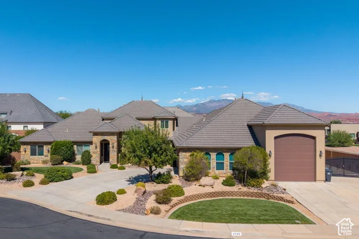 Stucco and stone exterior featuring an arched entryway, multiple arched windows, and an integrated garage with an arched door
