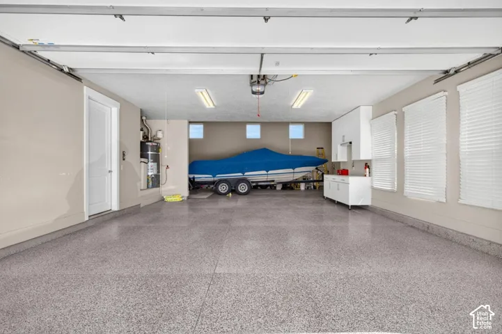 Spacious garage featuring a speckled epoxy flooring, white cabinetry, integrated sink, and overhead lighting