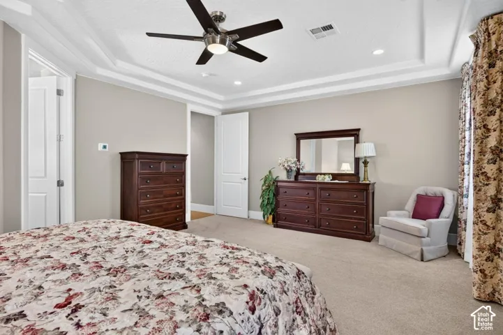 Tray ceiling with recessed lighting, ceiling fan, and light neutral wall color