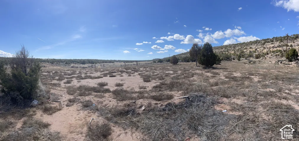 Expansive undeveloped land featuring natural vegetation and distant rolling hills