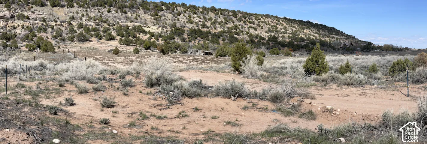 Expansive natural landscape featuring varied terrain, scattered native shrubs, and distant hills with sparse vegetation
