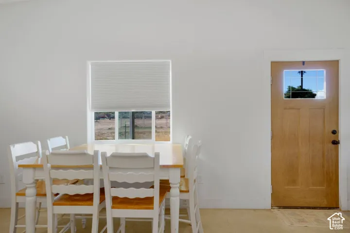 White interior walls, wood-finish flooring, wood entry door with glass panel, window with cellular shade