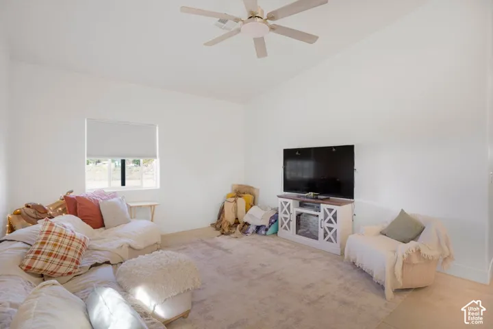 Vaulted white ceiling with a ceiling fan, recessed window, and light-toned flooring