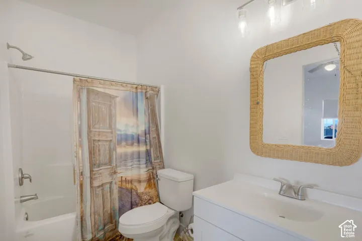 White vanity with an integrated sink and chrome faucet, square wicker-framed mirror, and a full-size bathtub with a shower