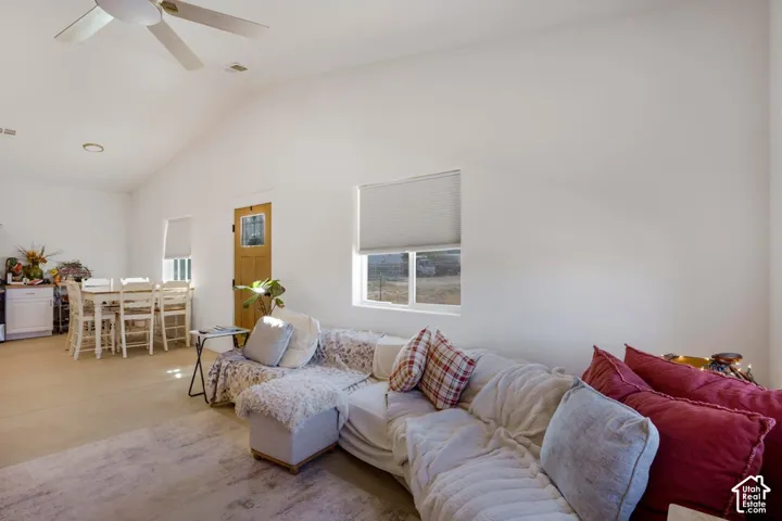 Vaulted ceiling with a ceiling fan, white walls, and a light wood-finish door with glass inserts