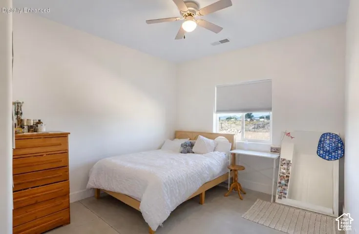 Window with roller shade, ceiling fan with integrated lighting, and light-colored flooring