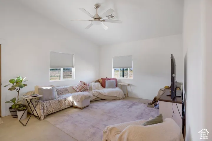 Vaulted ceiling with a ceiling fan, white walls, and two windows