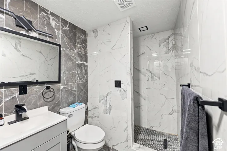 Contemporary bathroom featuring a vanity with an integrated sink, black-framed mirror, walk-in shower with mosaic tile flooring, and contrasting wall tiling