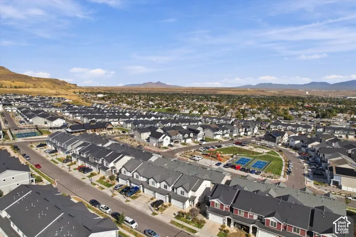 Residential development with uniform housing, mountain backdrop, community green space, and sports courts