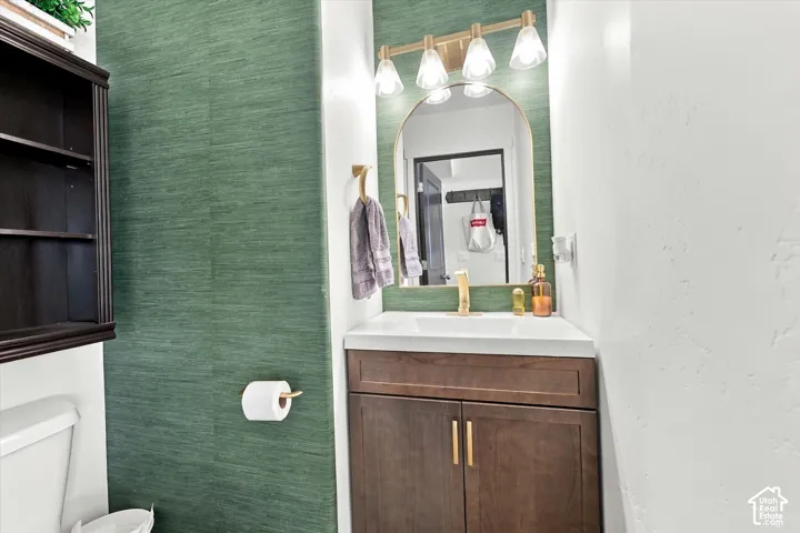 Wood-finish vanity with gold-tone hardware, a white countertop, and an arched mirror