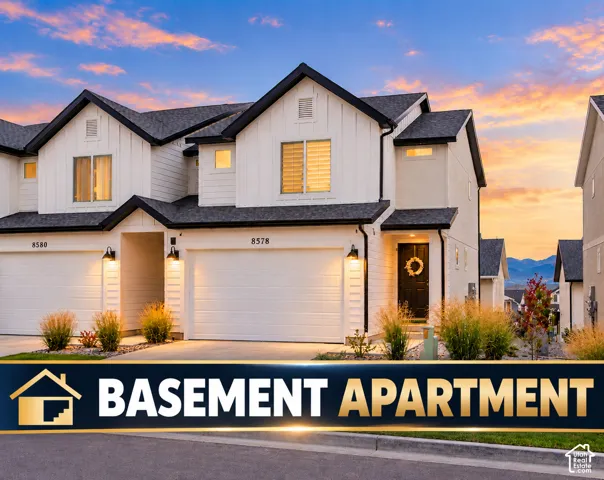 White siding exterior with black trim, integrated two-car garage, dark entry door, and exterior lighting fixtures