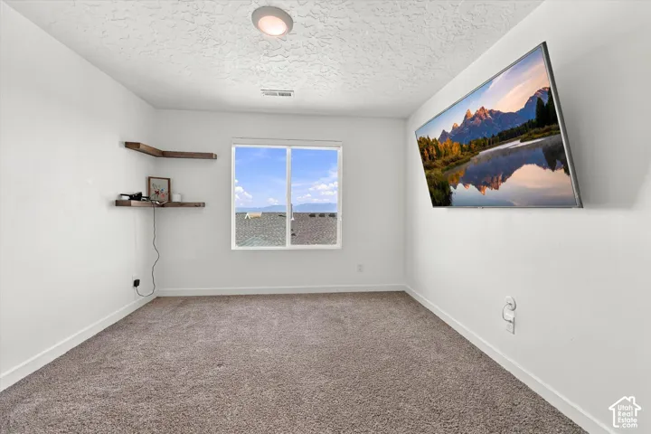 Recessed ceiling light, corner wall shelves, wall-mounted television, and a window with white trim