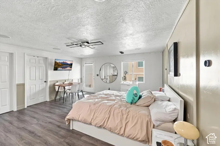 Wood-finish flooring, accent wall paneling, modern ceiling light fixture, recessed ceiling speakers, and white paneled doors