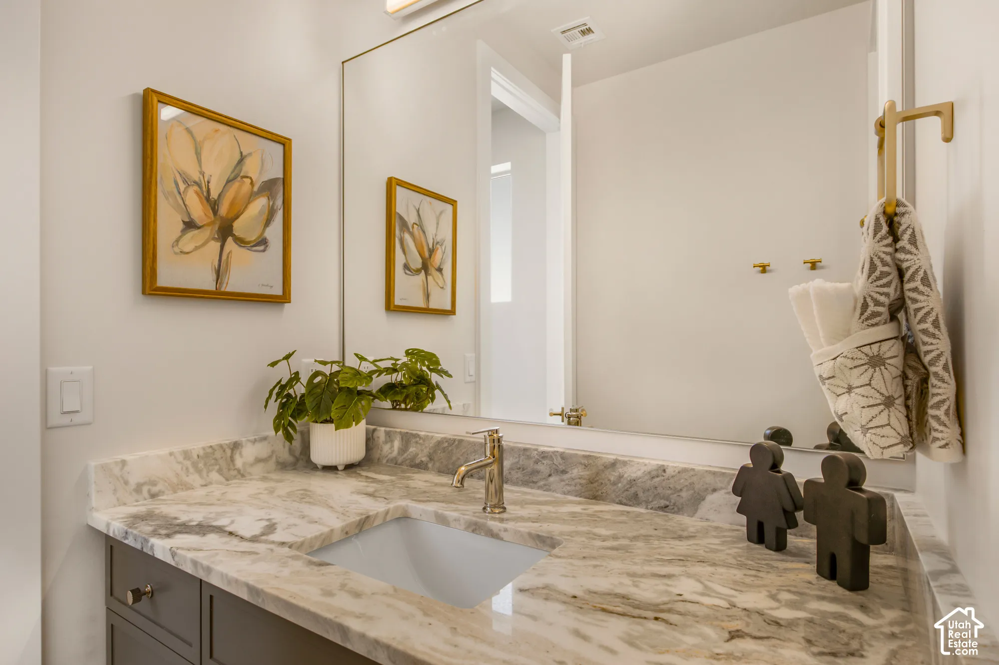 White vanity with a neutral-toned stone countertop, integrated sink, and polished nickel faucet
