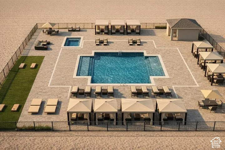 Resort-style pool area with a large swimming pool, integrated spa, surrounding paver patio, multiple cabanas, and a separate pool house