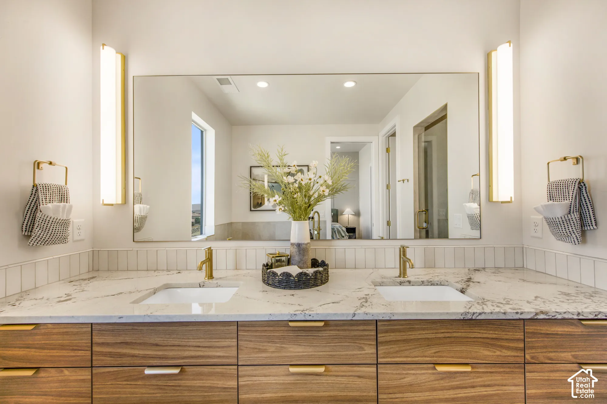Dual vanity with wood-finish cabinetry, stone countertop, undermount sinks, and gold-tone fixtures