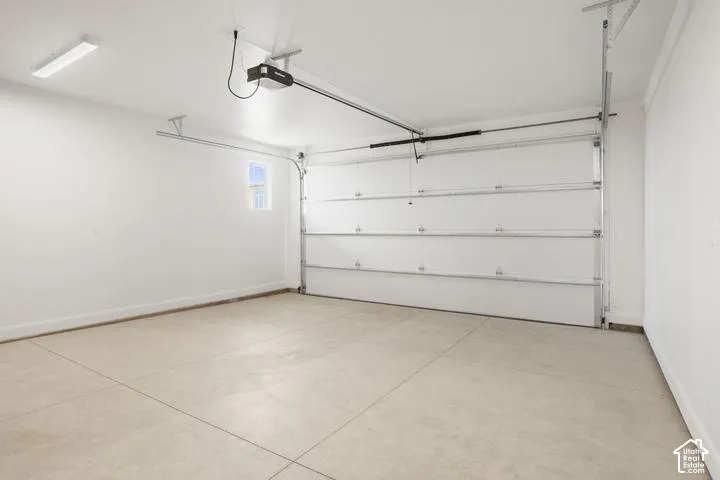 Garage featuring an automatic overhead door, concrete flooring, and a single window
