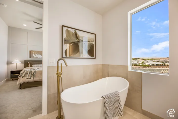 Freestanding soaking tub with a floor-mounted brass-finish faucet, accompanied by a large window
