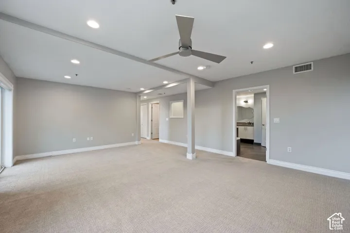 Spacious room featuring neutral carpet, recessed lighting, a modern ceiling fan, and a sliding glass door