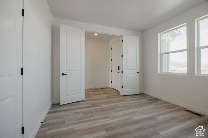 Light wood-finish flooring, white walls, two double-hung windows, and recessed lighting