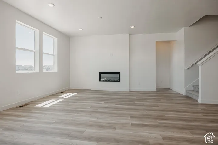 Wood-finish flooring throughout, recessed lighting, and an electric fireplace with a dark finish