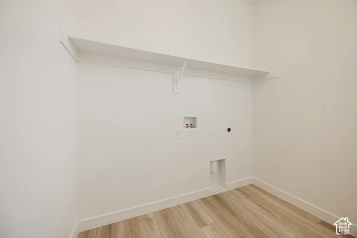 Utility space featuring wood-finish flooring, a wall-mounted shelf, and appliance connections