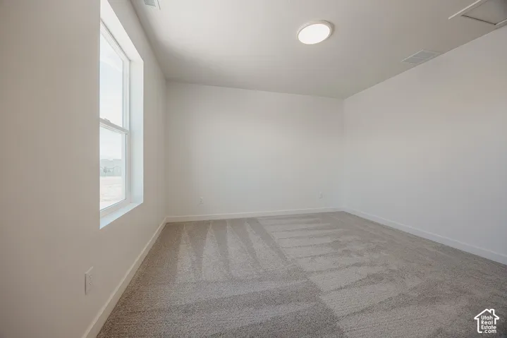 White wall finish, light gray carpeting, recessed ceiling lighting, and a single window