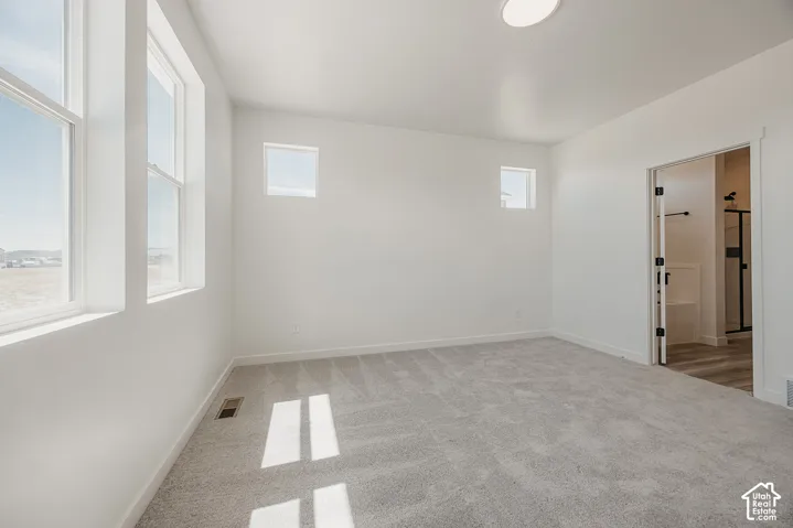 Recessed lighting and multiple windows illuminate this room featuring light gray carpeting