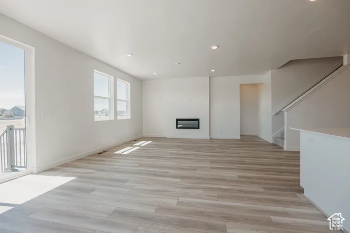 Wood-finish flooring, recessed lighting, and a modern fireplace with a black frame