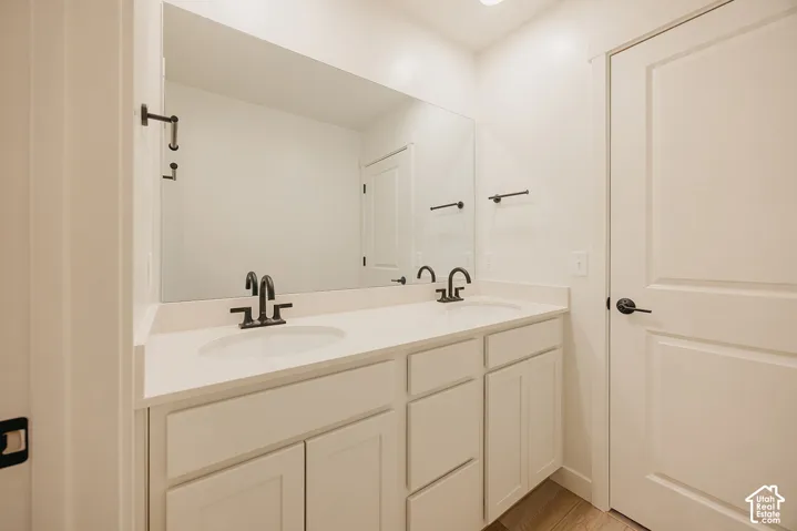 Dual sink vanity with white cabinetry, light-toned countertop, and matte black fixtures