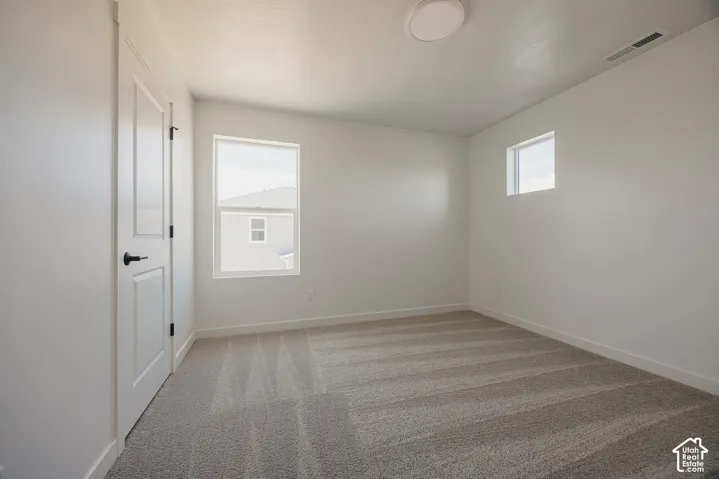Neutral-toned carpeting, white painted walls, and white trim throughout