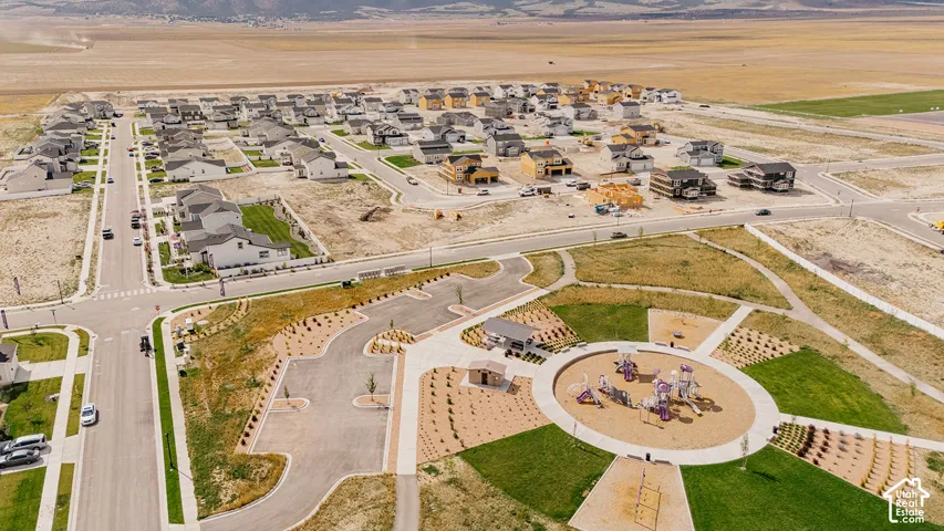 Newly developed residential area featuring a community park with playground, extensive green spaces, and paved pathways