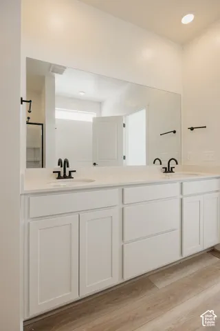 Double vanity with white cabinetry, light-toned countertops, and black fixtures