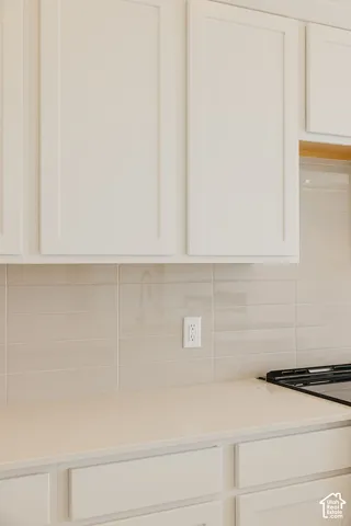 White shaker-style cabinetry, light-toned countertop, subway tile backsplash, and a built-in cooktop