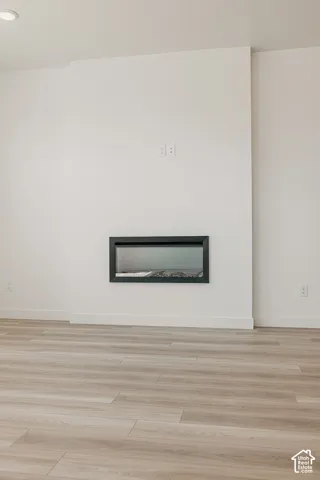 Modern living space featuring a linear gas fireplace insert with contemporary black frame, warm wood-finish flooring, and clean white drywall construction