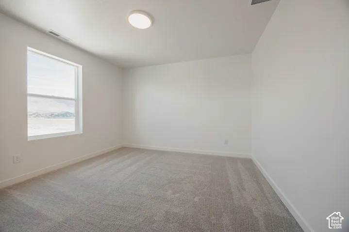 Light-filled room featuring a single window, recessed ceiling light, and neutral-toned carpeting