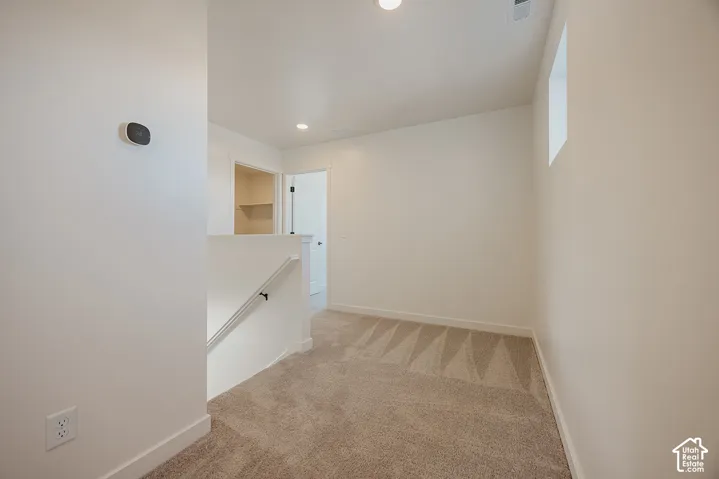 Carpeted landing with white walls, recessed lighting, and a built-in thermostat