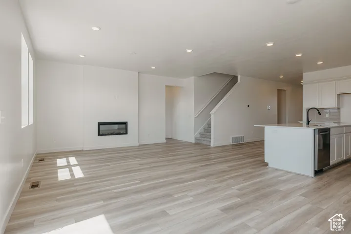 Open concept living area featuring wood-finish flooring, recessed lighting, and a linear electric fireplace