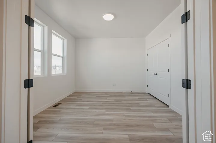 Bright room featuring wood-finish flooring, two large windows, a flush-mount ceiling light, and a double-door closet with dark hardware
