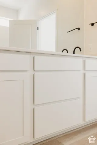 White shaker cabinetry with a light-toned countertop, matte black fixtures, and wood-finish flooring