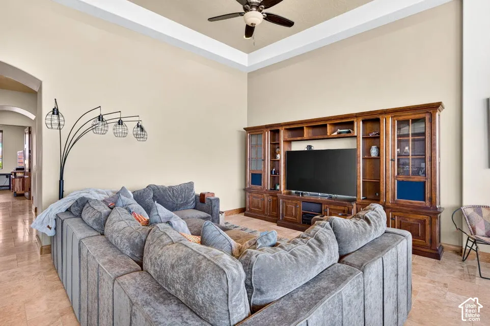 Expansive living area featuring a tray ceiling, integrated ceiling fan, and a built-in media center with glass-front cabinetry