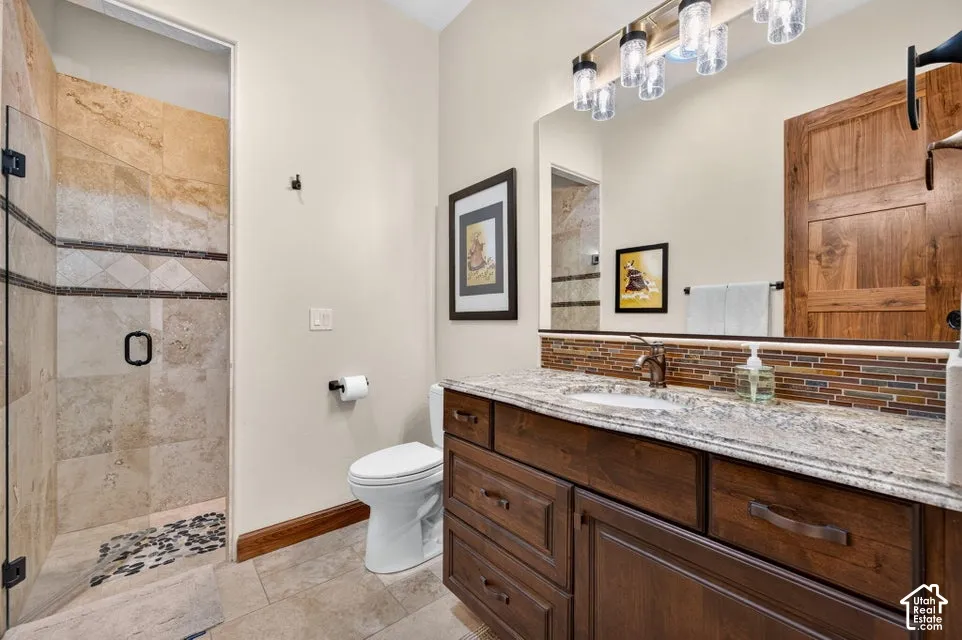 Walk-in shower with natural stone tile, glass enclosure, and river rock shower floor