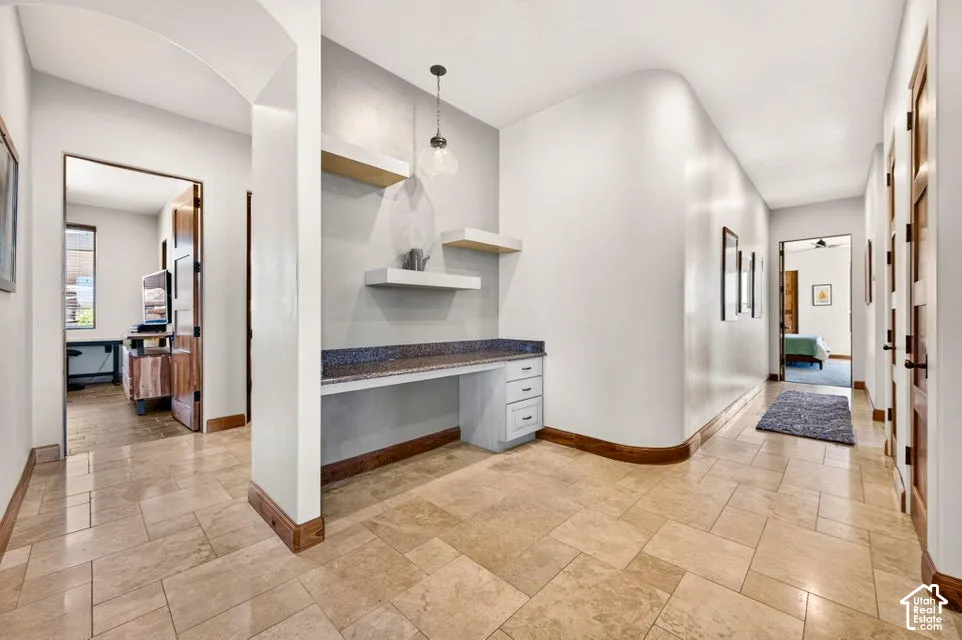 Tiled flooring, built-in desk with stone-finish countertop, pendant lighting, and wood-finish doors
