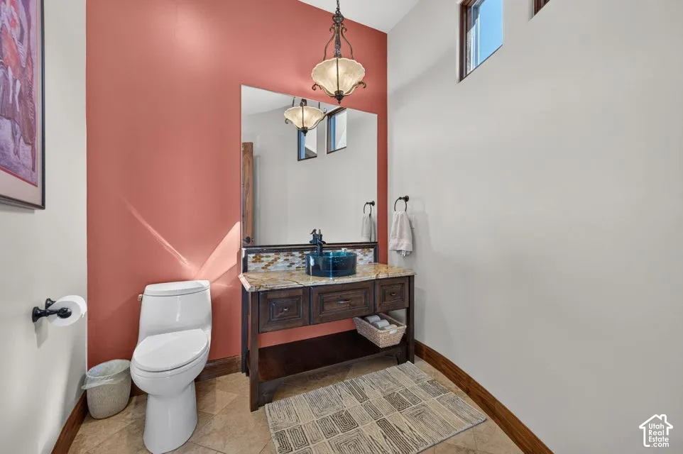 Vanity with a vessel sink, decorative backsplash, and an overhead pendant light