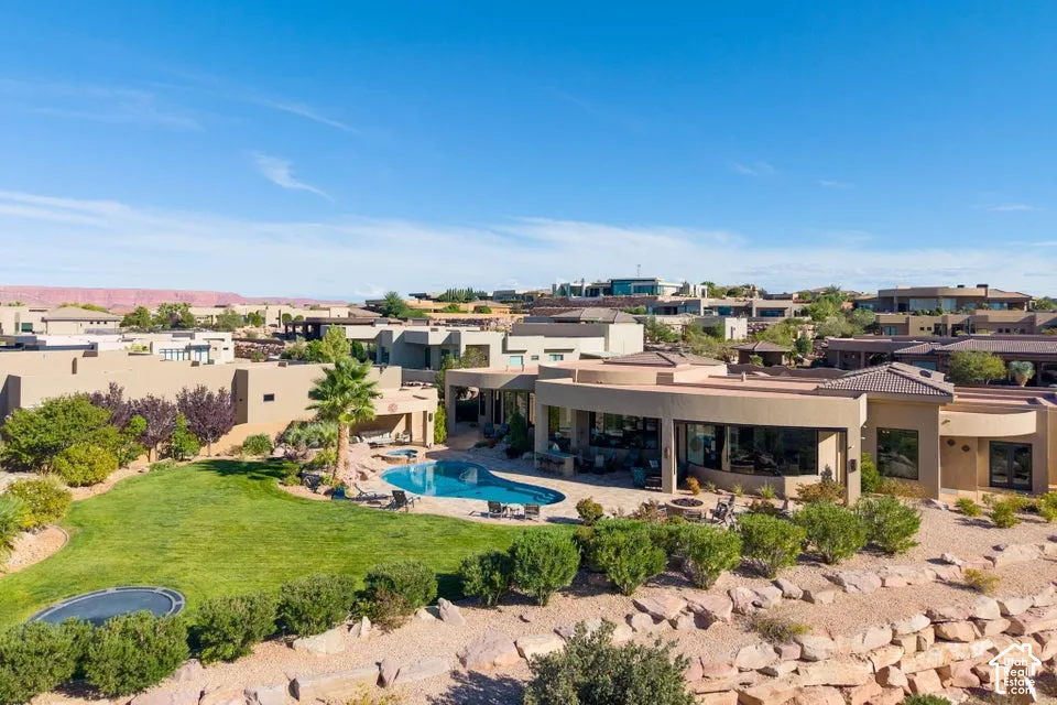 Terraced backyard featuring a curved pool, expansive lawn, and surrounding desert landscaping