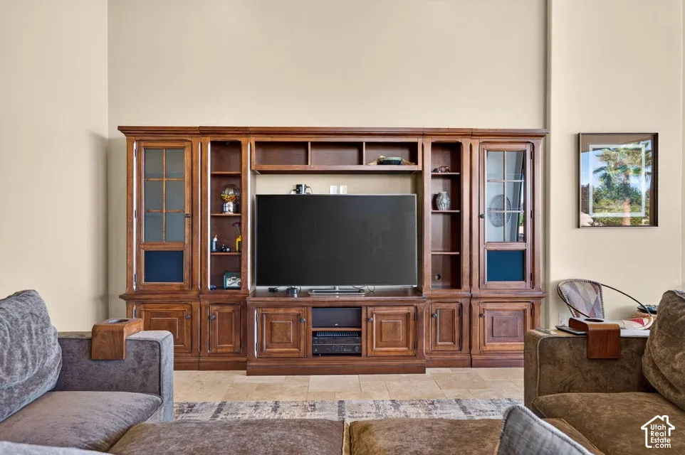 Built-in wood entertainment center with glass-front cabinets and open shelving, positioned on tile flooring