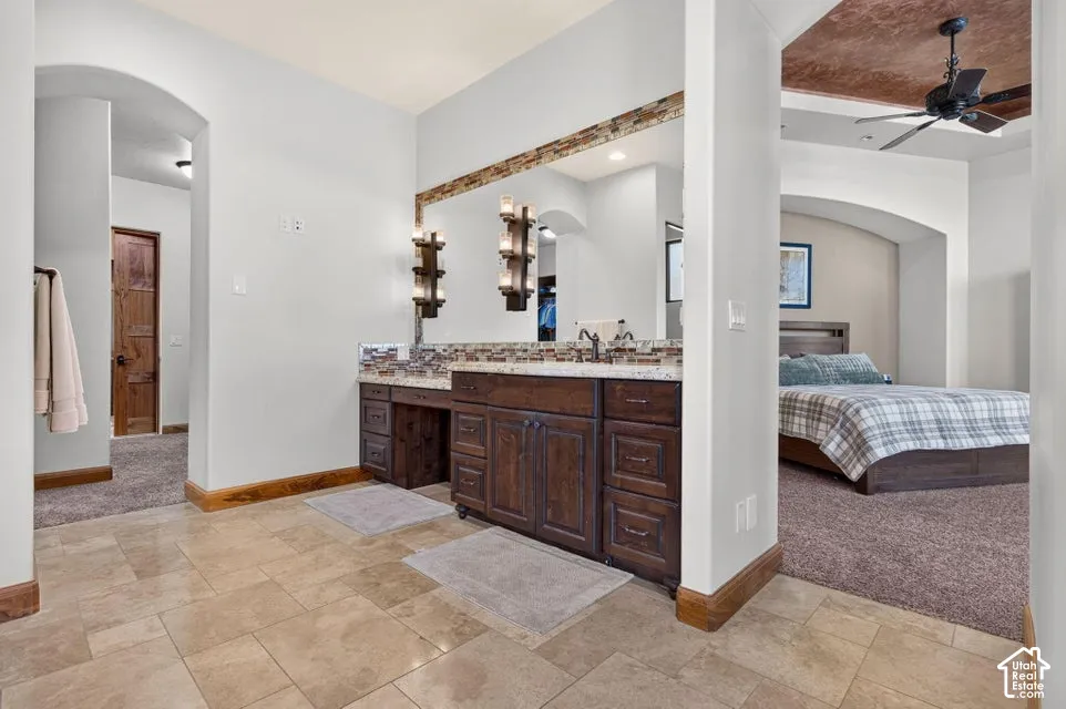 Dual sink vanity with dark wood-finish cabinetry, stone countertop, and decorative tile backsplash